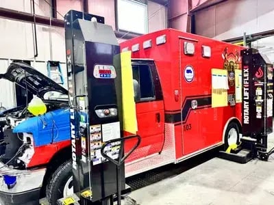 Ambulance patient module elevated on hydraulic lifts during the remounting process to prepare for chassis replacement and extended EMS service life.