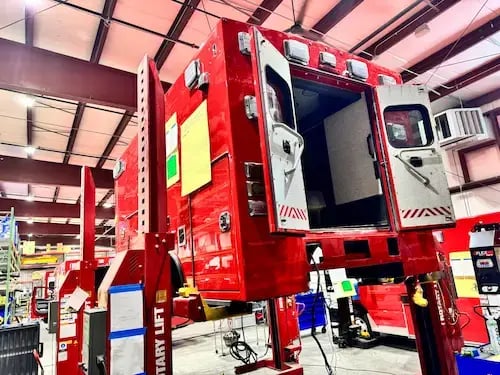 Ambulance patient module elevated to provide access for remounting, wiring, and structural refurbishment.