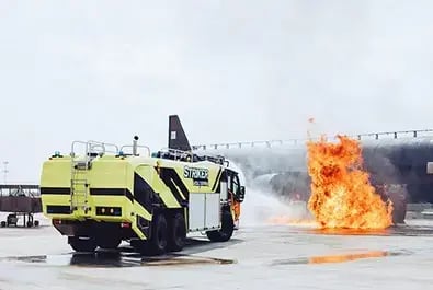 Oshkosh Striker ARFF vehicle deploying fire suppression capabilities during a live aircraft rescue and firefighting training exercise.