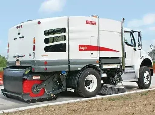 Elgin Eagle street sweeper cleaning a roadway in a construction area, featuring side and gutter brooms for municipal street sweeping, debris removal, and pavement maintenance operations.