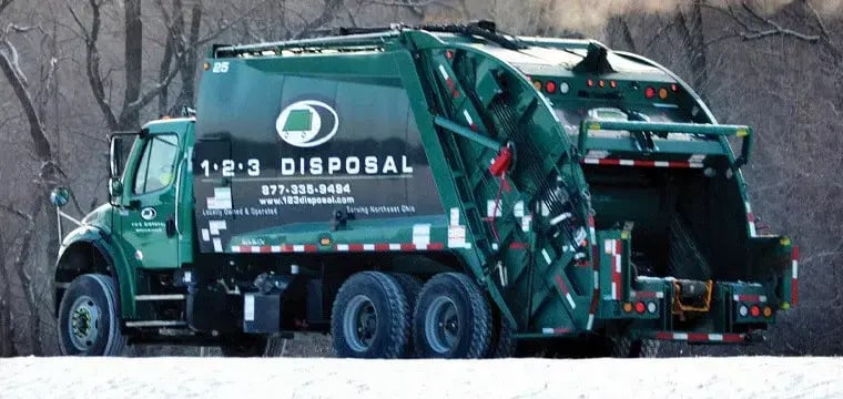 123 Disposal rear loader garbage truck operating in a residential area during winter conditions, featuring a rear-loading compaction system designed for curbside trash and municipal solid waste collection.