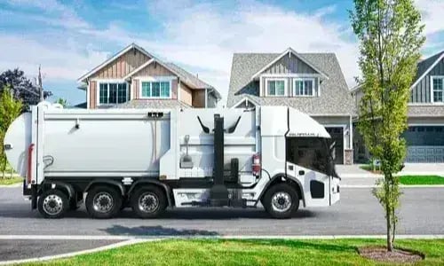 Electric refuse truck operating in a residential neighborhood, providing sustainable, zero-emissions waste collection and environmentally responsible sanitation services.
