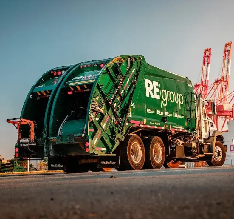 McNeilus split-body rear loader refuse truck designed for simultaneous trash and recycling collection, improving route efficiency and reducing operating costs.
