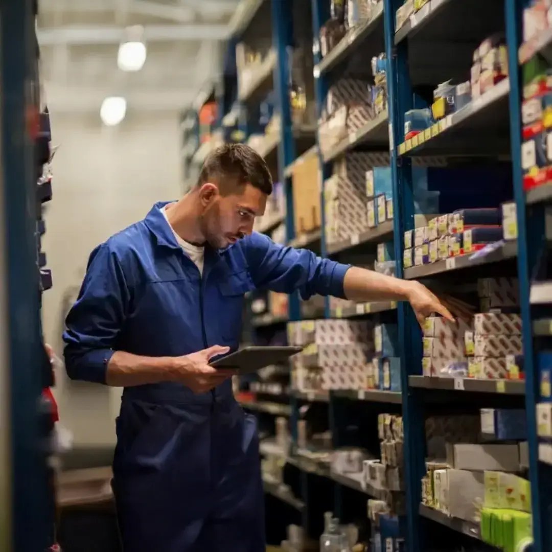 Parts specialist reviewing inventory with a tablet to locate components for warranty service, supporting accurate parts selection and efficient equipment repairs.