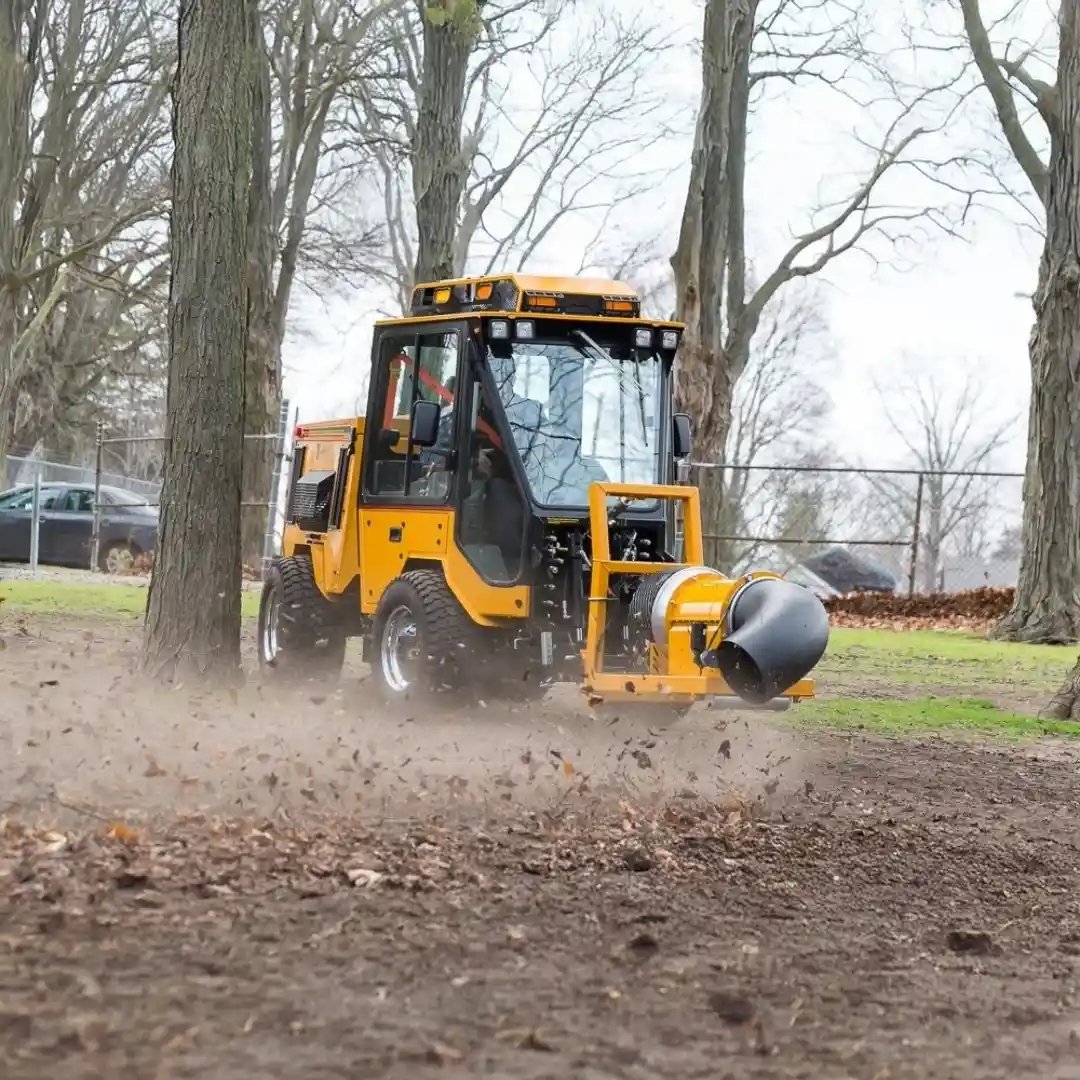 Trackless MT7 municipal tractor equipped with a front-mounted debris blower for clearing leaves, grass clippings, and debris from parks, trails, and public spaces.