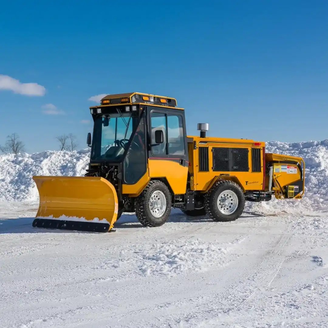 Trackless MT7 municipal tractor equipped with a front snowplow and rear snow blower for efficient snow removal on roads, sidewalks, parking lots, and public spaces.