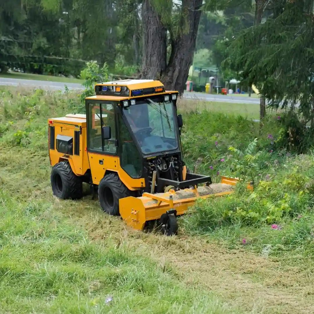 Trackless MT7 municipal tractor equipped with a front-mounted flail mower for cutting grass, brush, and roadside vegetation along parks, trails, and public spaces.
