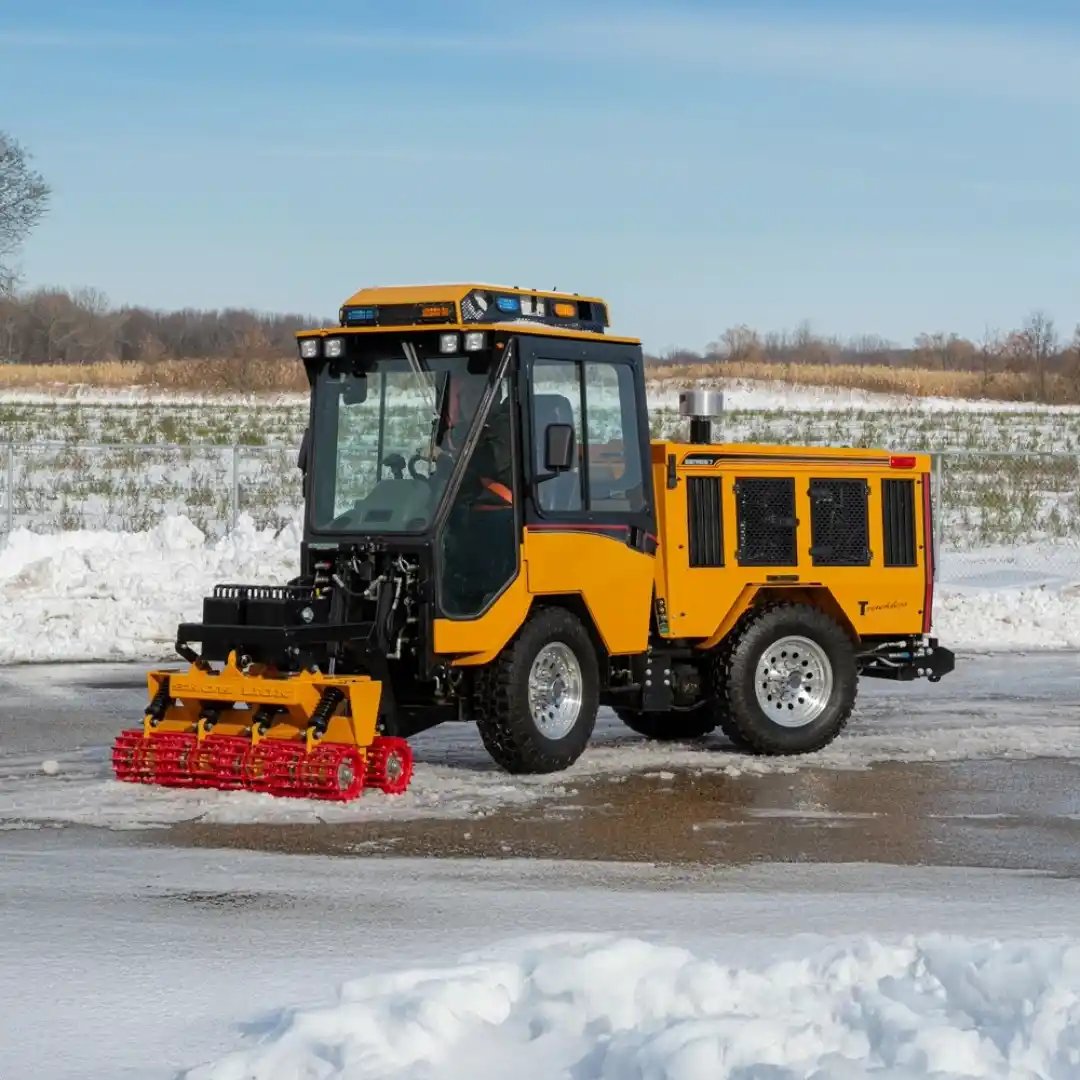 Trackless MT7 municipal tractor equipped with a front-mounted ice breaker attachment for breaking compacted snow and ice on roads, sidewalks, and public spaces.