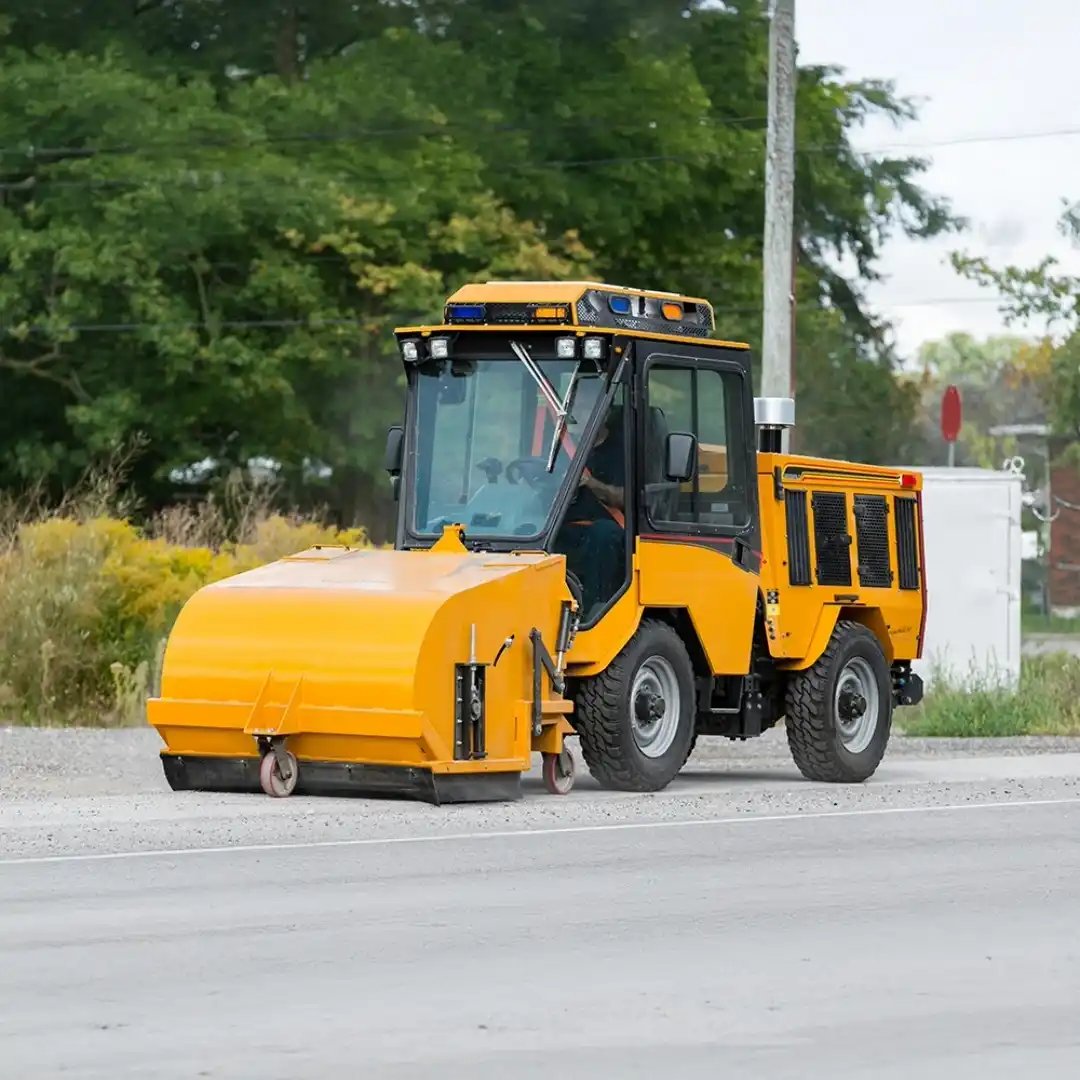 Trackless MT7 municipal tractor equipped with a front-mounted pickup sweeper for collecting leaves, debris, and litter from streets, sidewalks, and public spaces.