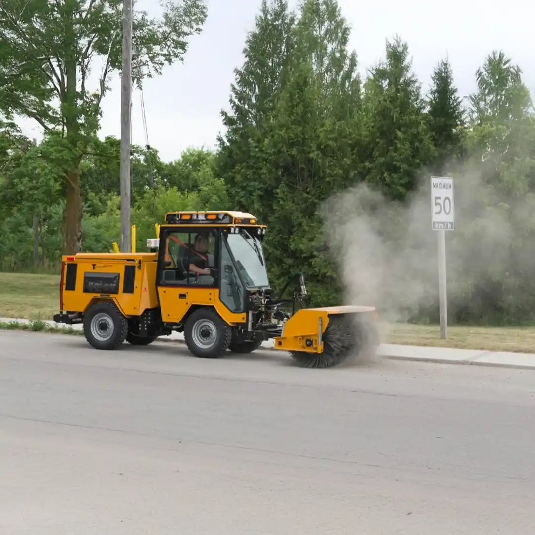 Trackless MT7 municipal tractor equipped with a front-mounted power angle sweeper for removing dirt, sand, and debris from streets, curbs, and public spaces.