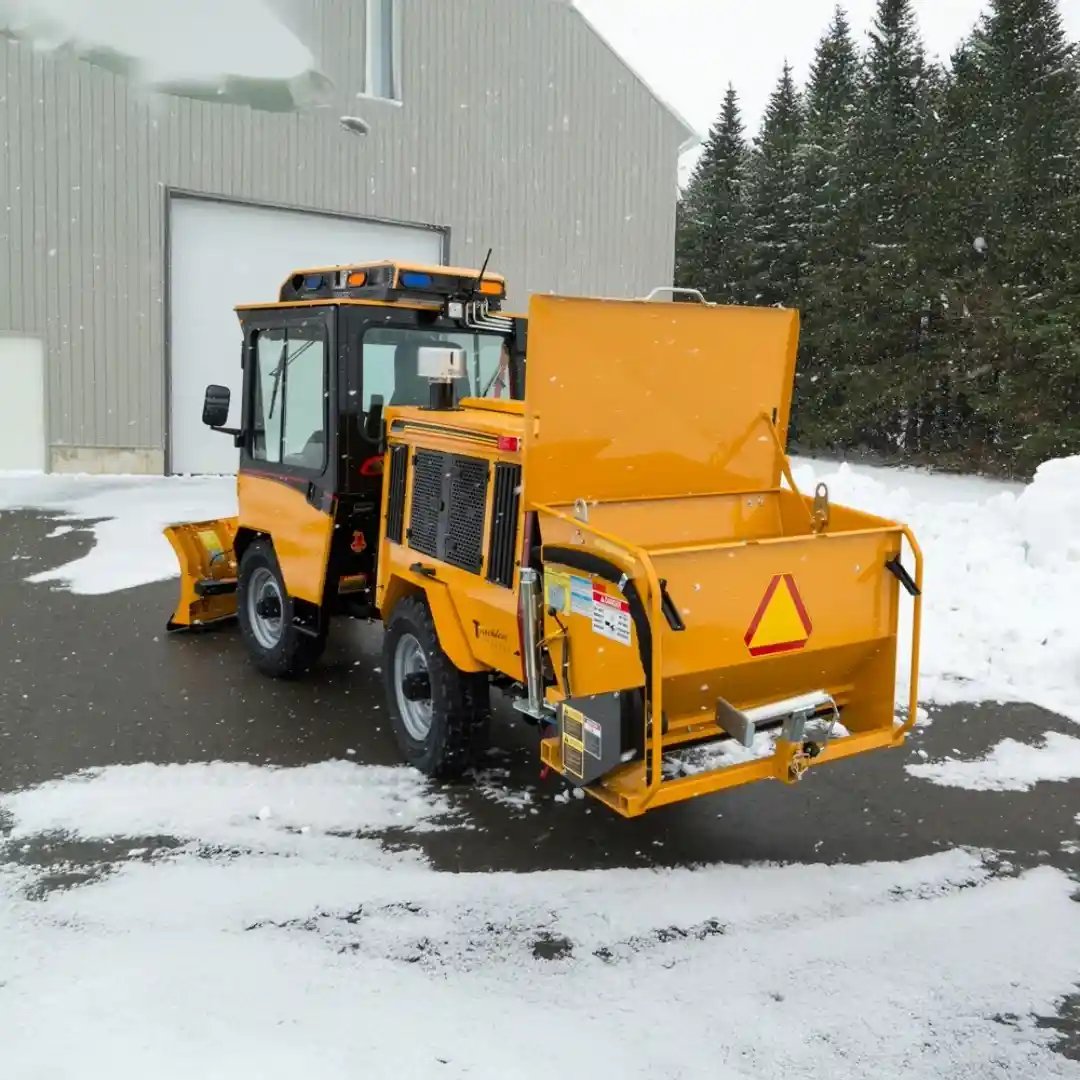Trackless MT7 municipal tractor equipped with a rear-mounted material spreader for applying salt, sand, or deicing materials during winter maintenance.