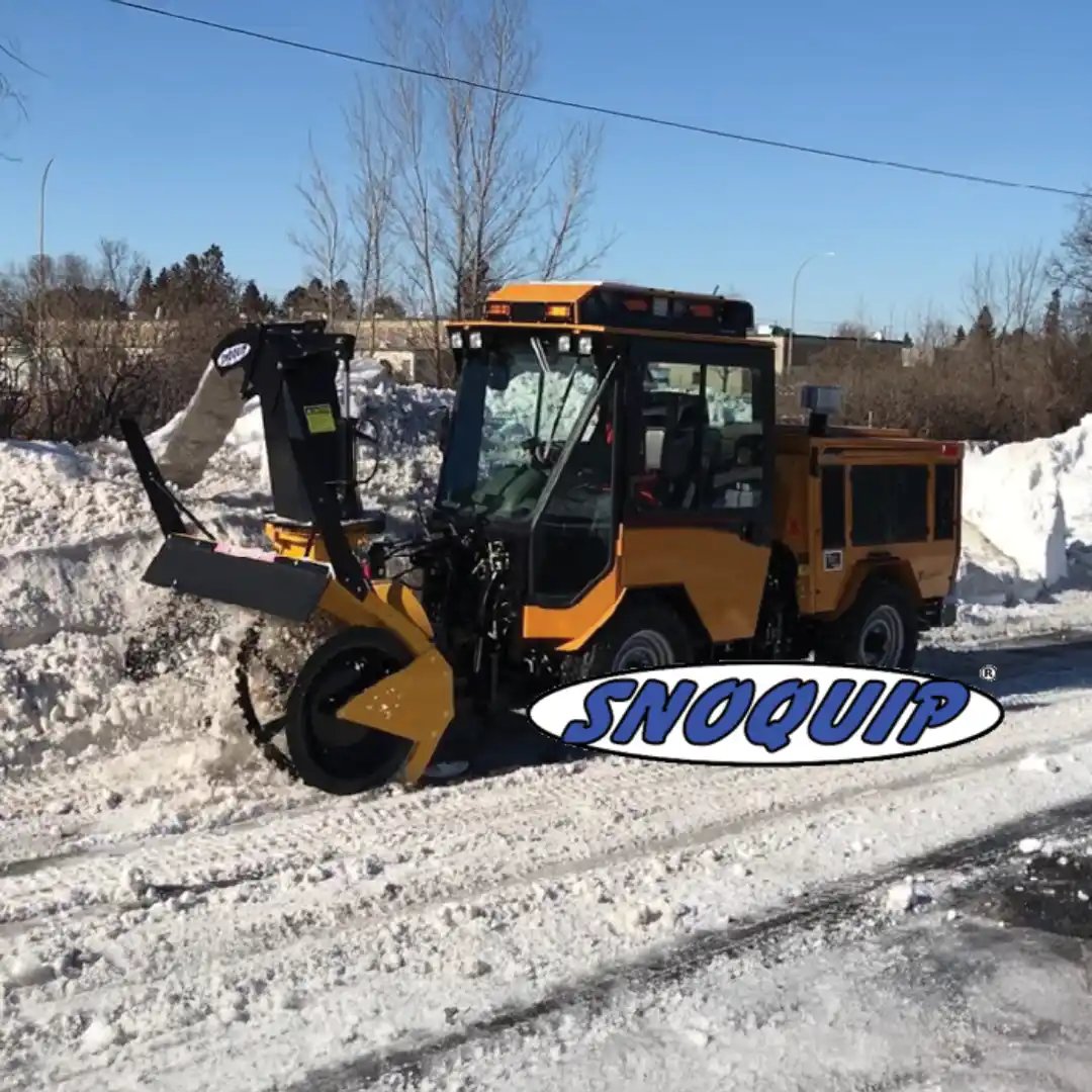 Trackless MT7 municipal tractor equipped with a SnoQuip front-mounted snow blower for clearing deep snow along roads, curbs, and public spaces,