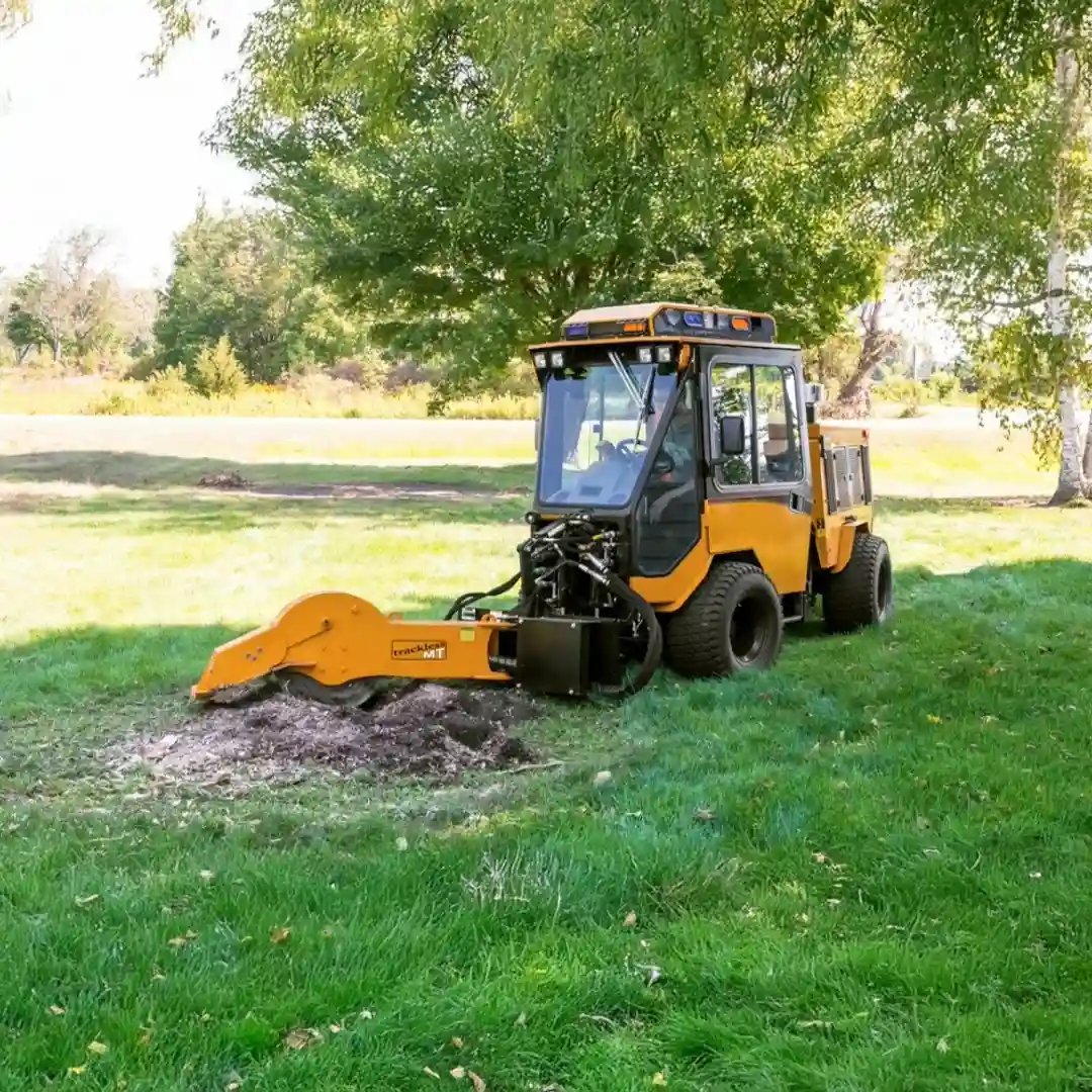 Trackless MT7 municipal tractor equipped with a front-mounted stump grinder for removing tree stumps in parks, green spaces, and municipal landscapes.