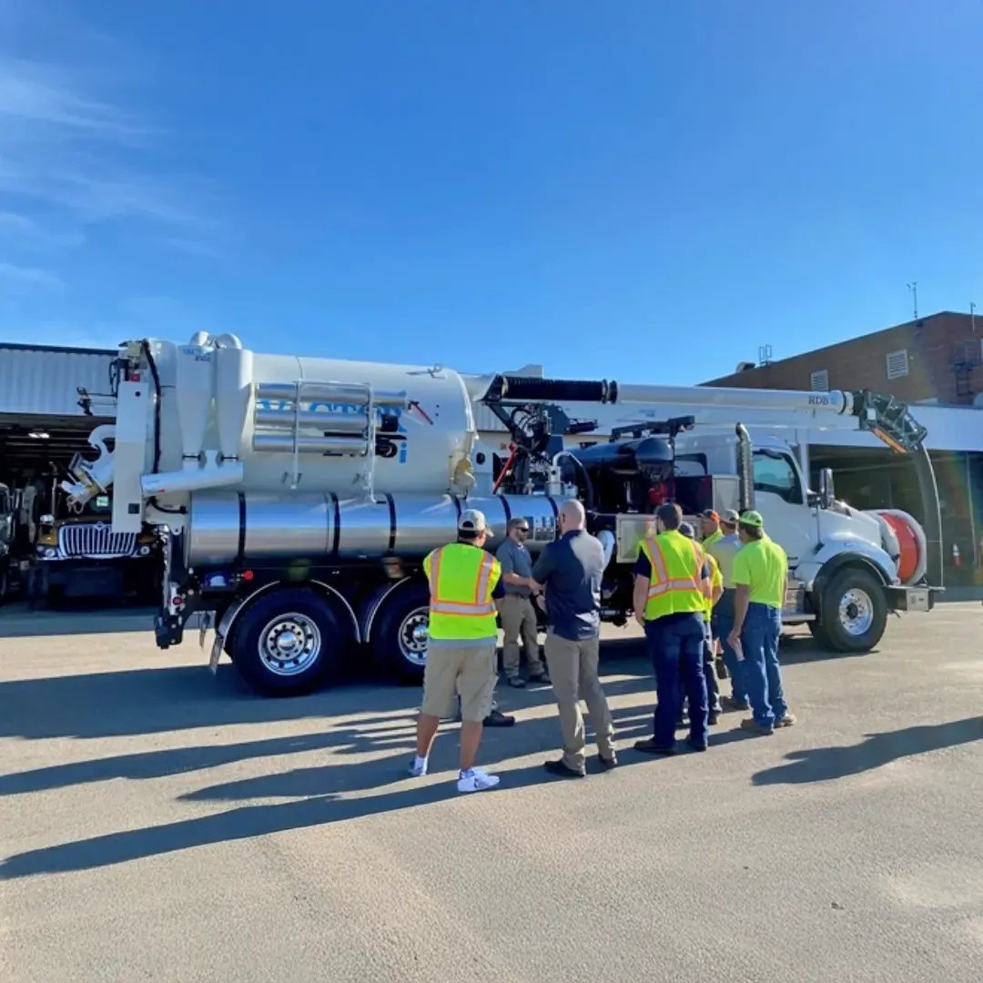 Group of professionals gathered around a Vactor combination sewer cleaner during hands-on equipment training, reviewing operation, safety features, and maintenance procedures.