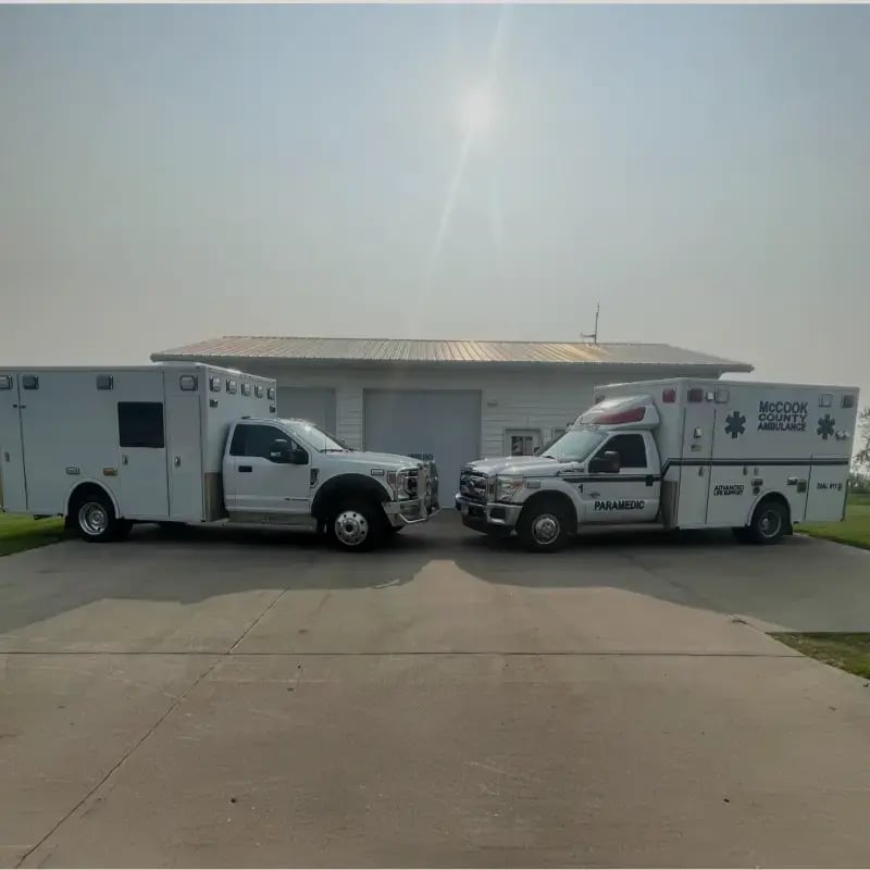 Two ambulances parked side by side outside a service facility, representing emergency medical services and patient transport solutions.