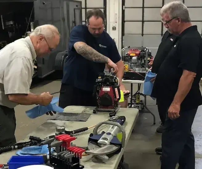 Technicians performing preventive maintenance and inspection on Hurst extrication tools during a hands-on service training session.
