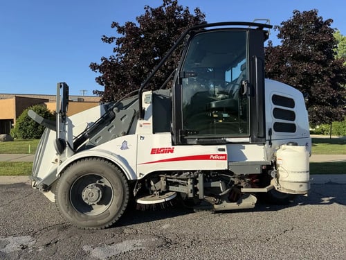 Driver-side profile of a 2016 Elgin Pelican NP street sweeper.