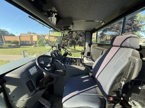 Cab interior with passenger seating and dual operator controls on a 2016 Elgin Pelican NP street sweeper.