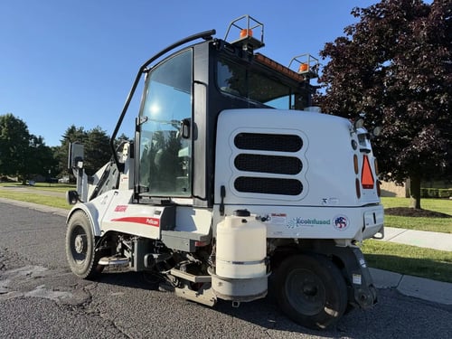 Rear driver-side angle of a 2016 Elgin Pelican NP street sweeper.