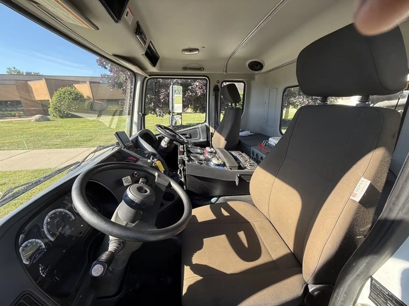 Driver-side interior of a 2013 Elgin Whirlwind street sweeper with dual-operator controls.