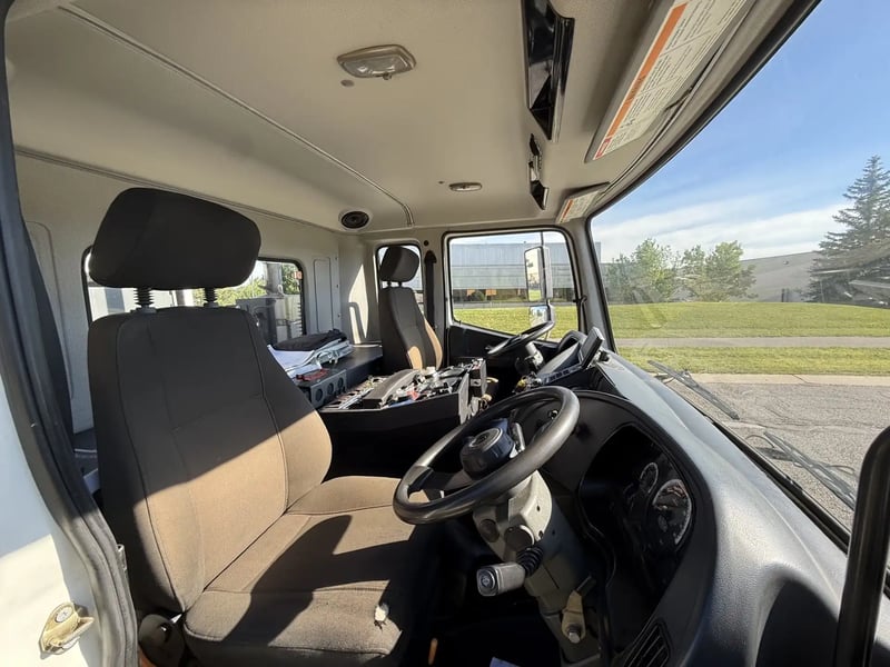 Passenger-side interior of the operator cab in a 2013 Elgin Whirlwind street sweeper.
