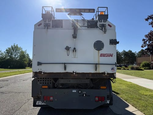 Rear view of a 2013 Elgin Whirlwind street sweeper showing the hopper and rear work platform.
