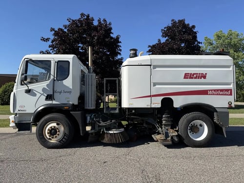 Driver-side profile of a used 2013 Elgin Whirlwind regenerative air street sweeper on an Autocar Xpeditor chassis.