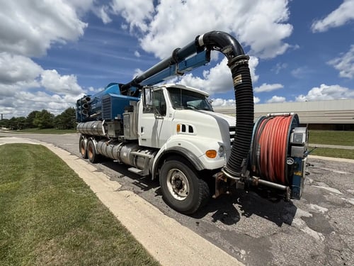 Front driver-side view of a 2006 Vactor 2100 featuring the hydraulic boom and front hose reel.