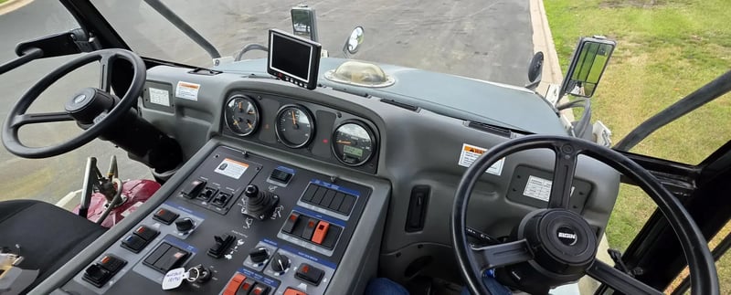 Dashboard and dual steering controls inside a 2015 Elgin Pelican NP Dual street sweeper.