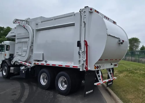 Rear driver side angle of 2026 McNeilus Atlantic Commercial 40 yard front loader refuse truck