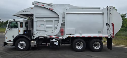 Driver side profile of a McNeilus Atlantic 40-yard front load waste collection truck.