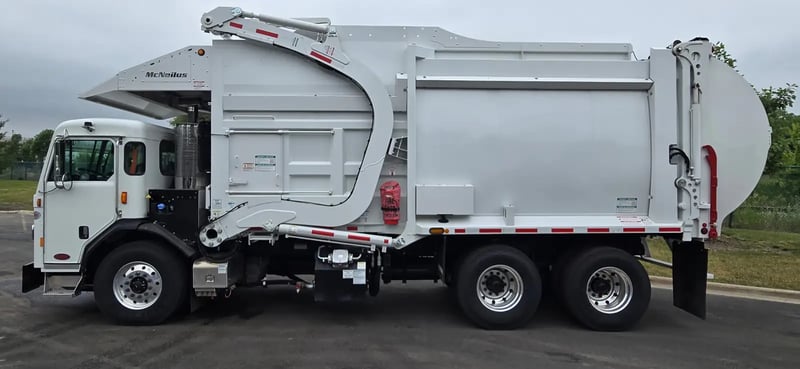 Driver side profile of a McNeilus Atlantic 40-yard front load waste collection truck.