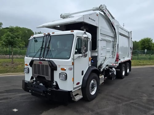 Front driver-side view of a McNeilus Atlantic 40-yard front loader garbage truck.