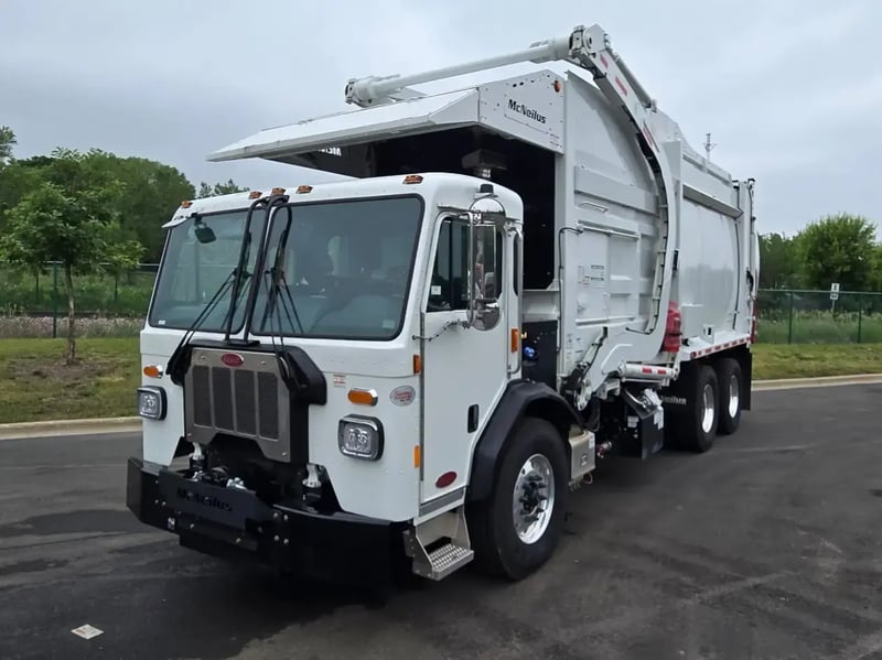 Front driver-side view of a McNeilus Atlantic 40-yard front loader garbage truck.