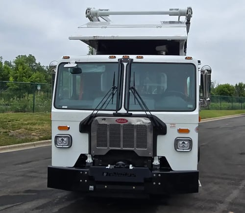 Front view of a McNeilus Atlantic 40-yard front loader refuse truck.