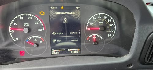 Instrument cluster and operating hours display inside a McNeilus Atlantic front loader refuse truck.