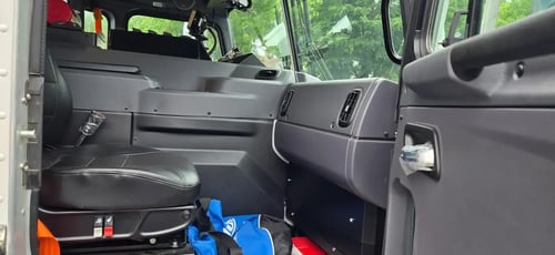Passenger side interior of a McNeilus Atlantic 40-yard front loader refuse truck featuring cab seating and controls.