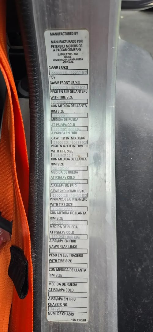 Peterbilt certification label and vehicle weight information on a McNeilus Atlantic front loader truck.