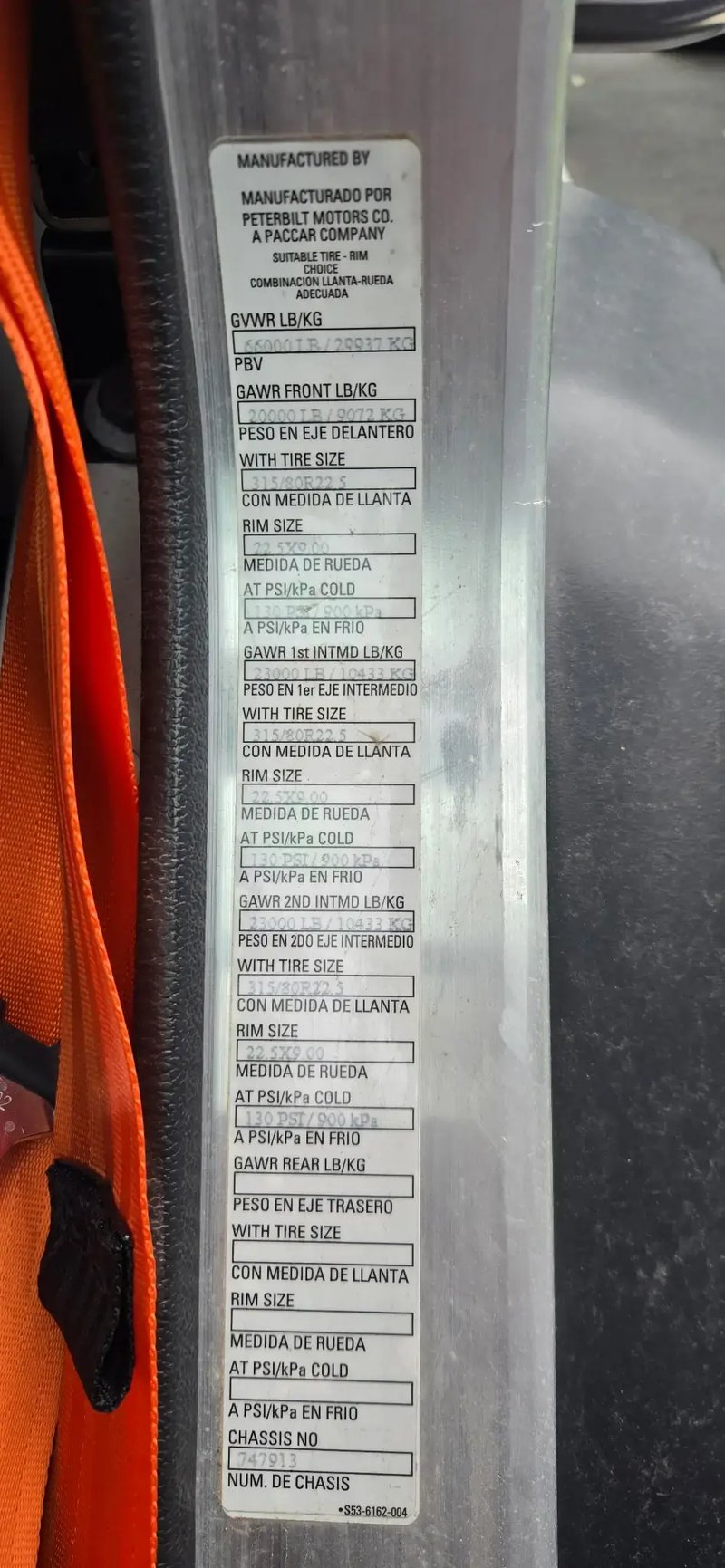 Peterbilt certification label and vehicle weight information on a McNeilus Atlantic front loader truck.