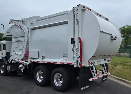 Rear driver-side angle of a McNeilus Atlantic 40-yard front loader refuse vehicle.