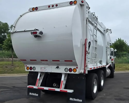 Rear passenger-side view of a McNeilus Atlantic 40-yard front loader waste collection truck.