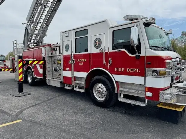 Pierce aerial ladder truck with an extended ladder, enclosed crew cab, and equipment compartments designed for firefighting and emergency response operations.