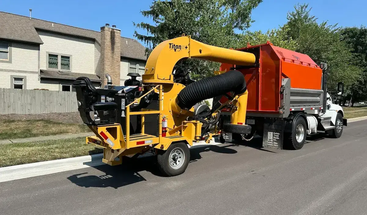 Titan Leaf pro Plus trailed leaf vacuum directing leaves into Titan Chipper Cap mounted on truck chassis