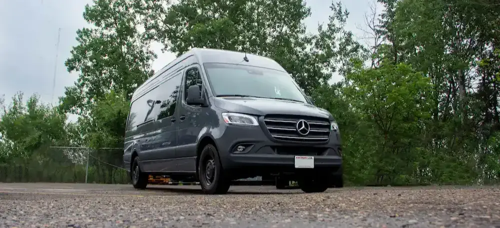 Command vehicle with a high-roof van body, tinted side windows, and exterior communications support configuration.