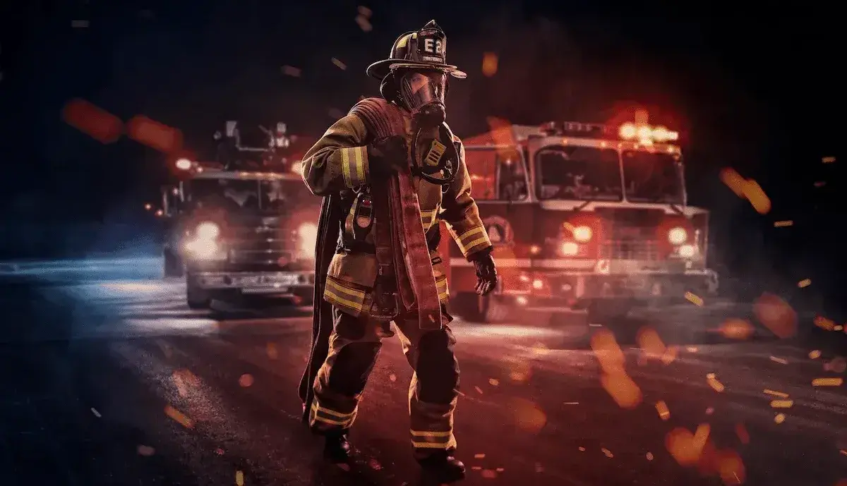 Firefighter in full turnout gear and SCBA standing with a fire hose in front of two fire trucks during emergency response operations.