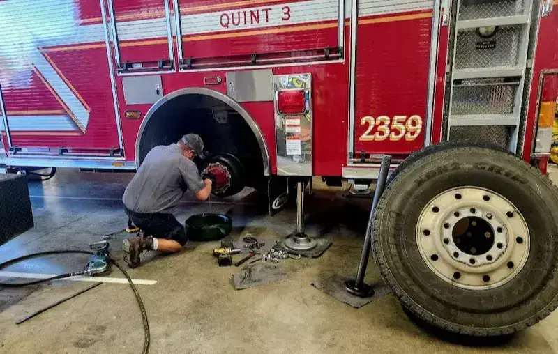 Fire apparatus technician performing scheduled preventative maintenance on a fire truck to improve fleet reliability, safety, and emergency response readiness.